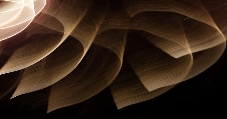 Abstract golden light trails flowing across a dark background, representing connected security operations and continuous cyber monitoring.